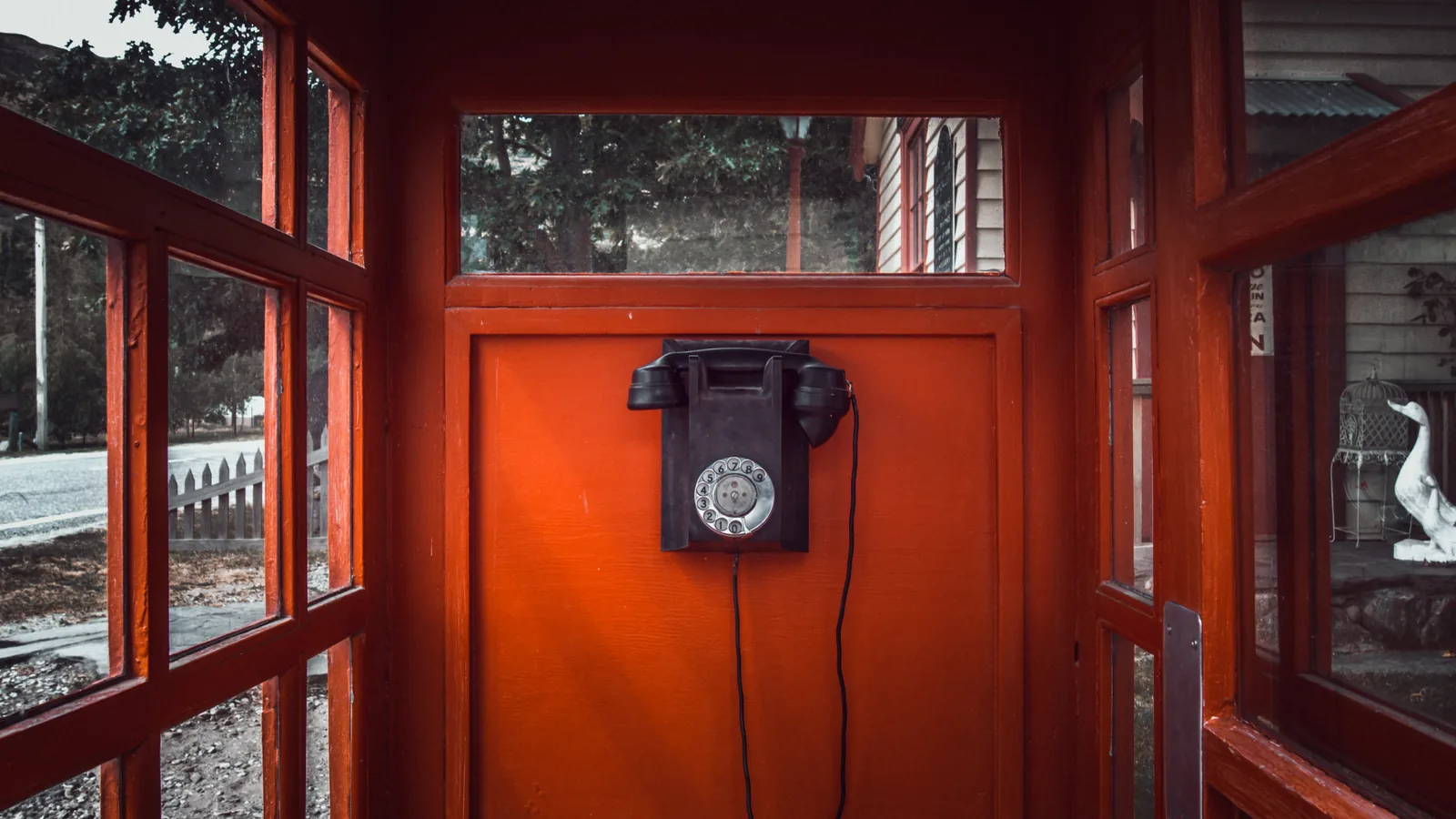 Un téléphone noir à cadran accroché dans une cabine téléphonique rouge