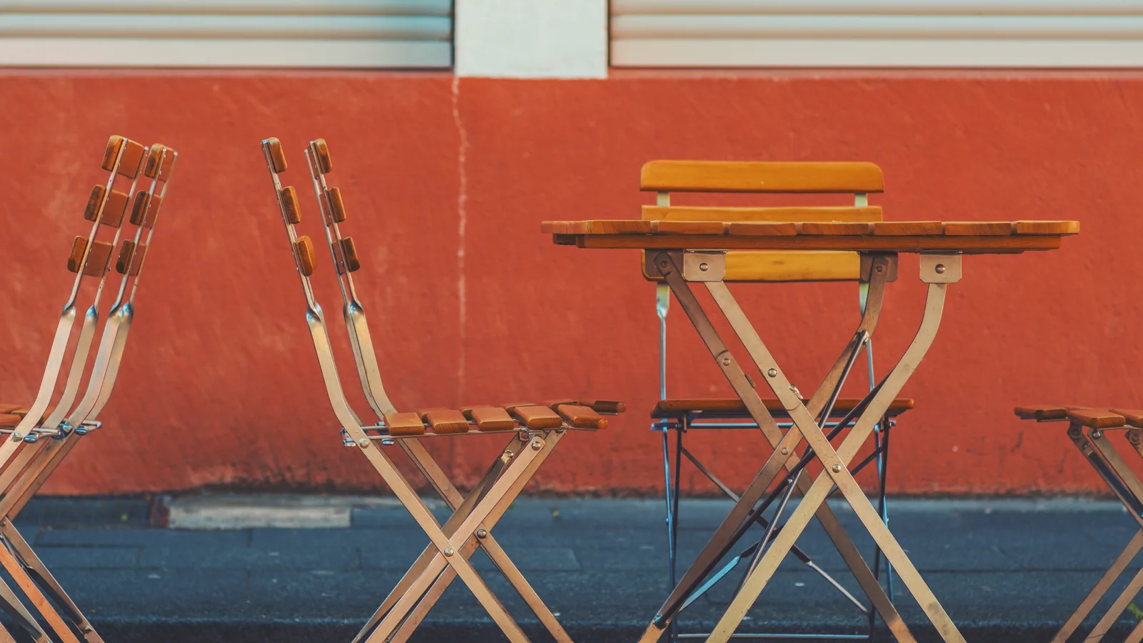 Des chaises et une table de terrasse vides devant un mur orange